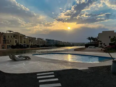 an empty swimming pool with a sunset in the background at Vibrant 3BR Villa - Free Pool & Lagoon Access At ElGouna in Hurghada