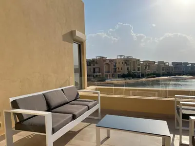 a couch on a balcony with a view of a city at Vibrant 3BR Villa - Free Pool & Lagoon Access At ElGouna in Hurghada