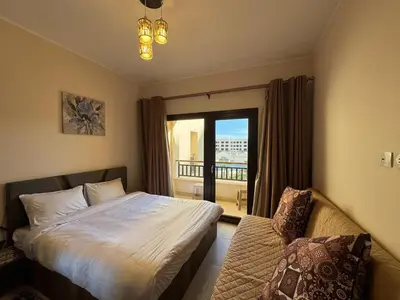 a bedroom with a bed and a window and a couch at Sun & Fun Aldau Heights one bedroom apartment in hurghada in Hurghada