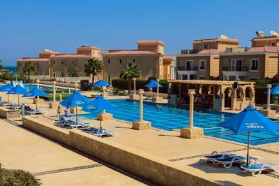 a pool at a resort with blue umbrellas and chairs at Selena Bay Resort in Hurghada