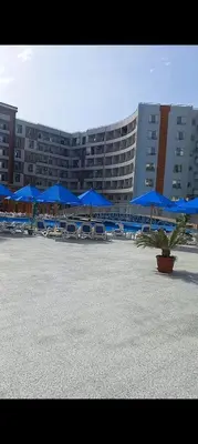 a large building with blue umbrellas and tables and chairs at Taiba Golden Resort in Hurghada