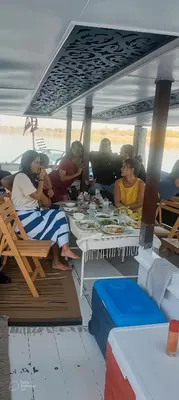 a group of people sitting at tables on a boat at sailboat in Luxor