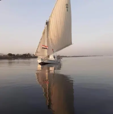 a sailboat on the water with its reflection in the water at sailboat in Luxor