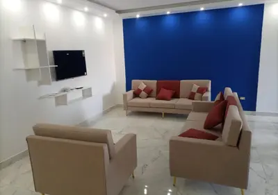 a living room with two couches and a blue wall at Fanadir Bay - beach & Aquapark in Hurghada