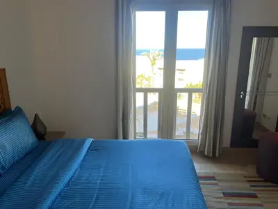 a bedroom with a blue bed with a view of the beach at Seaview Apartment in Azzurra Sahl Hasheesh 2 bedrooms in Hurghada