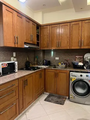 a kitchen with wooden cabinets and a washing machine at Sunflower cozy apartment in Hurghada