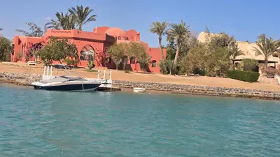 a boat docked in the water in front of a building at فيلا نوبيا بجوار بيتش الزيتونه in Hurghada