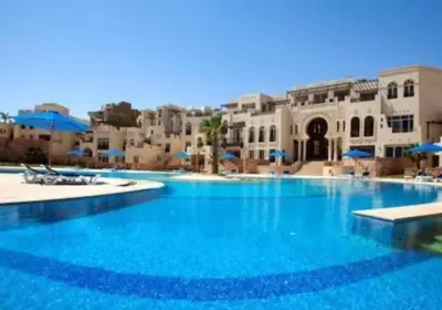 a large blue swimming pool with buildings in the background at Apartment Azzura Sahl Hasheesh with Private Garden and Sea view in Hurghada