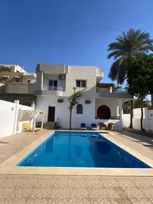 a villa with a swimming pool in front of a house at Villa Acamar in Al Karnak