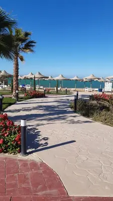 a sidewalk with umbrellas and the ocean in the background at Casablanca beach in Hurghada
