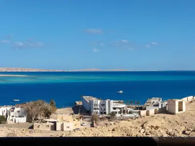 a group of white buildings on a beach next to the water at The View Island in Hurghada