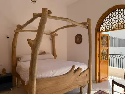 a bedroom with a wooden canopy bed with white sheets at El Bawaba Lodge & Luxury Retreat in Al Aqālitah
