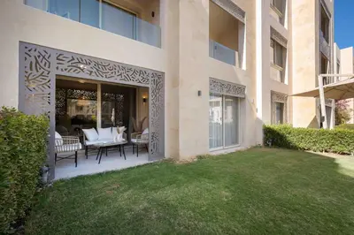 a building with a patio with chairs and a lawn at Mangroovy Stays El Gouna - BirdNest in Hurghada