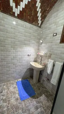 a bathroom with a sink and a blue mat at Lilys Garden Guest House in Jazīrat al ‘Awwāmīyah