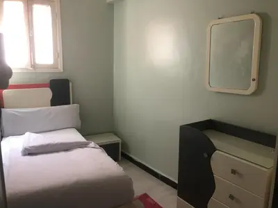 a small bedroom with a bed and a mirror at HAWATY NUBA DWeLL in Nag` el-Ramla