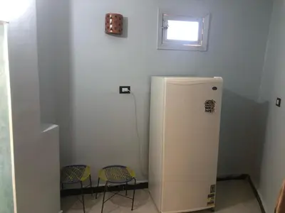 a white refrigerator in a room with two chairs at HAWATY NUBA DWeLL in Nag` el-Ramla