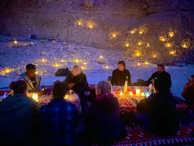 a group of people sitting around a table with candles at Life in Luxor in Nag` Naqsha