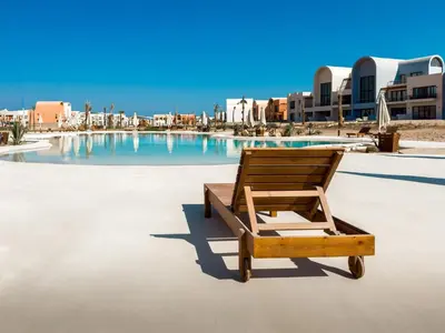 a wooden chair sitting in front of a swimming pool at Kamaran 2BR • Luxurious Retreat in Hurghada