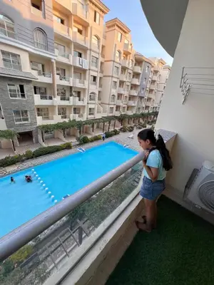 a young girl standing on a balcony looking at a swimming pool at Luxury One Bed Room Apartment in Hurghada