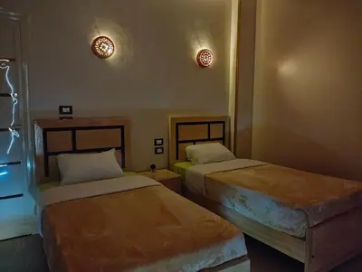 a room with two beds and two lights on the wall at Rayan Nubian Guest House in Aswan