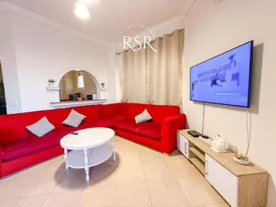 a living room with a red couch and a tv at Apartment with a private roof top , pool , Garden in Hurghada