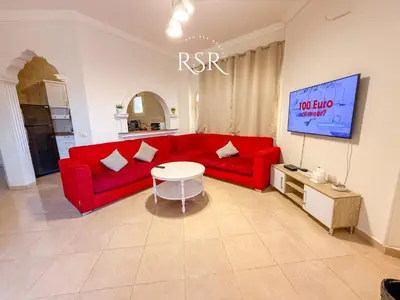 a living room with a red couch and a table at Apartment with a private roof top , pool , Garden in Hurghada