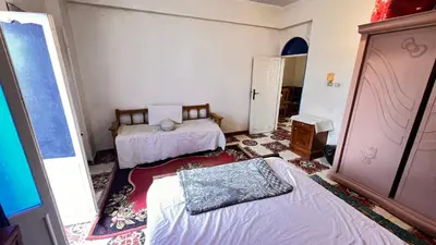 a small room with two beds and a window at Family Flat With Breakfast in Luxor