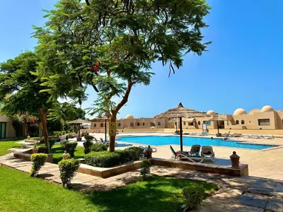 a resort with a swimming pool and trees and chairs at The view -Clubhouse in Hurghada