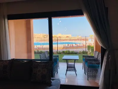 a living room with a view of a patio with a table and chairs at The Clubhouse Apartment in Hurghada