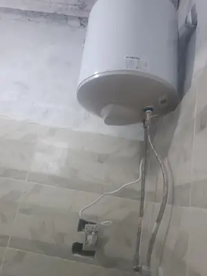 a white shower head hanging from a wall at Isis farm house in Al Aqālitah