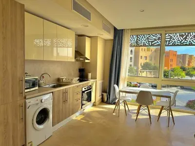 a kitchen with a sink and a table with chairs at One bedroom Mangroovy El Gouna in Hurghada