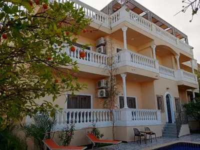 a large yellow building with a balcony and chairs at Elnahla Villa in Hurghada