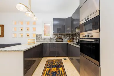 a kitchen with black cabinets and a stove top oven at Townhouse with roof terrace,balcony and large pool in Hurghada