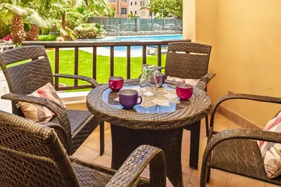 an outdoor table with chairs and glasses on a balcony at Townhouse with roof terrace,balcony and large pool in Hurghada