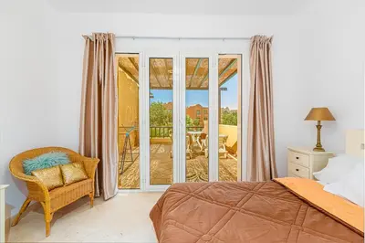 a bedroom with a bed and a chair and a balcony at Townhouse with roof terrace,balcony and large pool in Hurghada