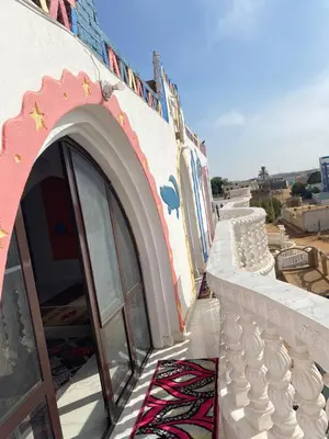 a building with a door and a rug on a balcony at Maleka nubian guest house in Jazīrat Suhayl