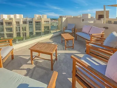 a patio with benches and tables on a roof at Cozy One Bedroom in Mangroovy in Hurghada