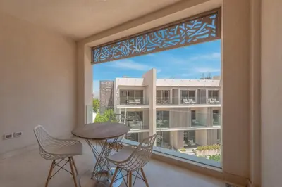 a balcony with a table and chairs and a large window at Cozy One Bedroom in Mangroovy in Hurghada