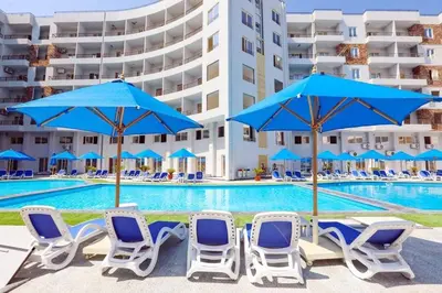 a group of chairs and umbrellas next to a swimming pool at Tiba Golden Resort Hurghada in Hurghada