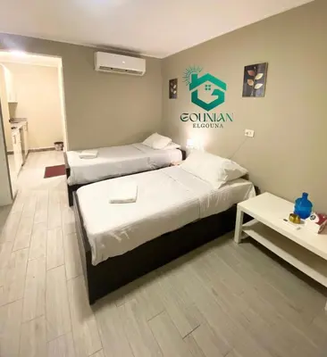 two beds in a room with a sign on the wall at Cozy studio in Bali in Hurghada