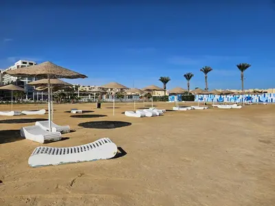 a sandy beach with white lounge chairs and umbrellas at Private Garden Studio Wi-Fi and Beach Access in Hurghada