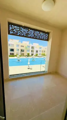 a room with a large window with a view of a tennis court at Cozy apartment in Mangroovy in Hurghada