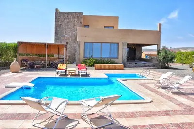 a swimming pool with chairs and a house at Luxury Sea-View Villa with Private Pool with Diving center & Beach access in Marsa Alam