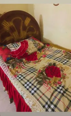 a bed with flowers on it with a wooden headboard at Nubian night in Jazīrat Suhayl