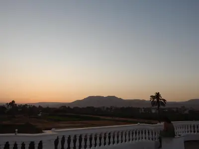 a woman sitting on a balcony watching the sunset at Villa Golden Mountain in Luxor