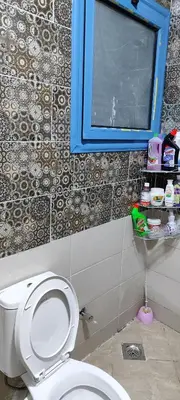 a bathroom with a white toilet and a blue window at Oasis marina in Hurghada