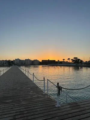 a person is standing on a pier near the water at Seafront Hotel Apartment with private beach in Hurghada