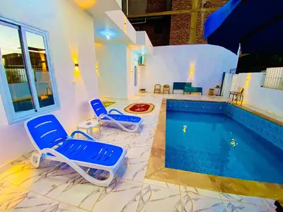 a pool with two blue chairs and a swimming pool at Taha Guest house in Luxor