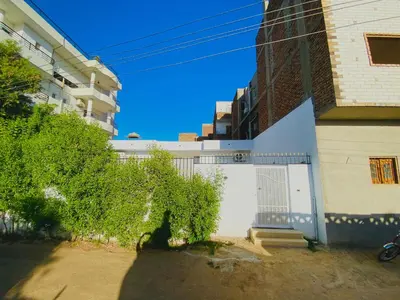 a building with a gate and a bush next to a building at Taha Guest house in Luxor