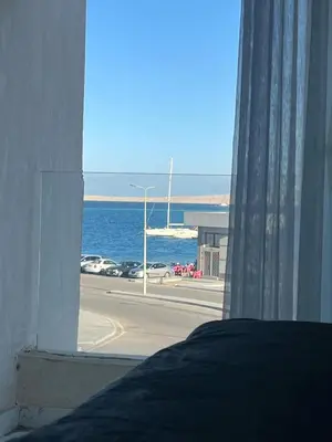 a bedroom window with a view of the ocean at Маленький голубий кит in Hurghada